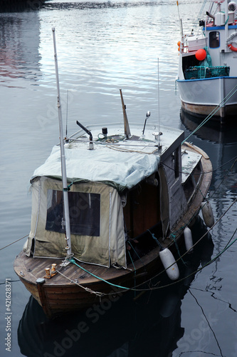 Small fishing boat. Old and dirty wooden boat moored to a pier.