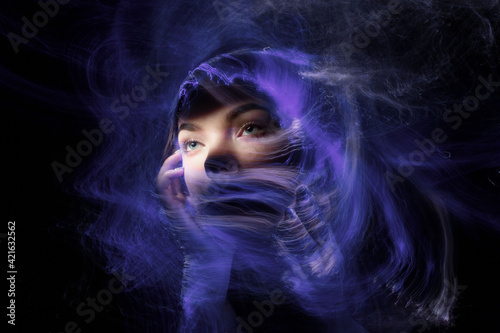 beautiful girl model with cosmic make-up on face  blue and purple color on dark background   longexposure foto