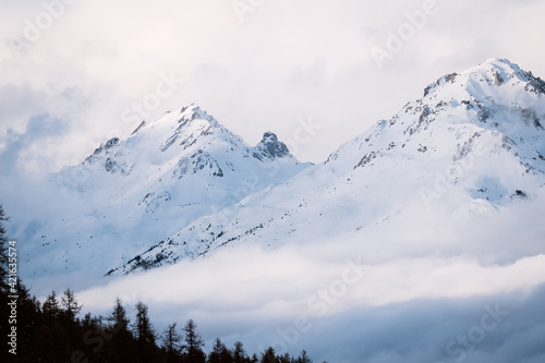 Foggy winter mountain landscape. Panoramic view of mountains near Brianson, Serre Chevalier resort, France. Ski resort landscape. Snowy mountains. Winter vacation. Misty morning in mountains photo