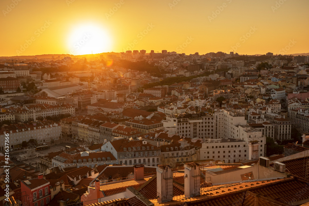 Beautiful yellow sunset in Lisbon, Portugal. Sun rays over red rooftops. Traveling seatination. Romantic vacation in beautiful city.