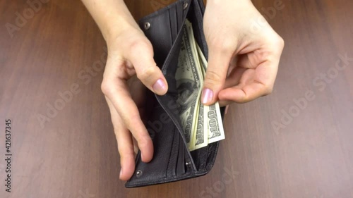 Women's hands hold a wallet and count dollars in it.4k