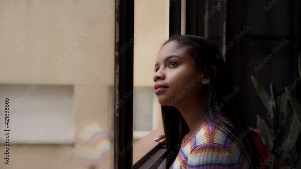 African American girl near the window. From home looking outside with a smile. African American girl near the window. From home looking outside with a smile.