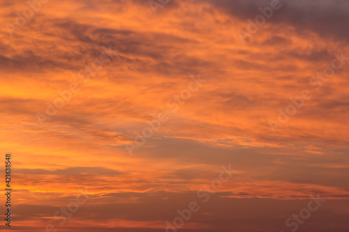 Epic Dramatic bright sunrise, sunset orange yellow red sky with clouds in sunlight background texture