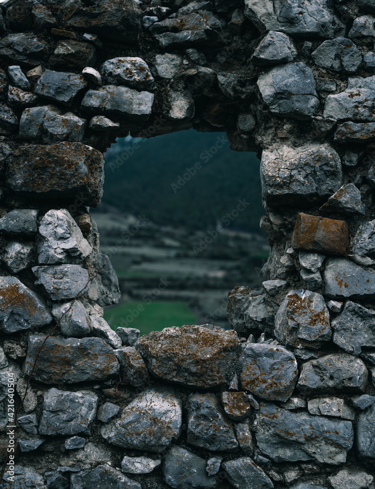 Antigua ventana de un castillo de piedra con paisaje verde de fondo. Campos y granjas en Cataluña, España. 