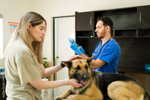 Woman petting her dog while the vet holds a vaccine