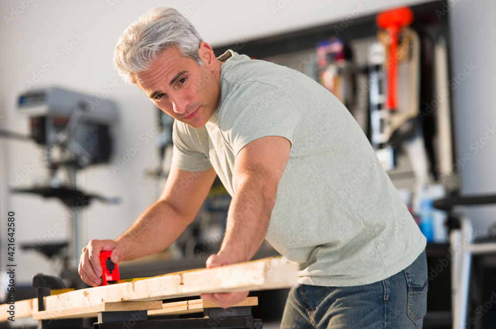 Handyman measuring a piece of wood in workshop Handyman measuring a piece of wood in workshop