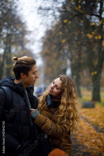 young couple looks at each other tenderly. young loving couple hugs in the park with yellow leaves on the background.
