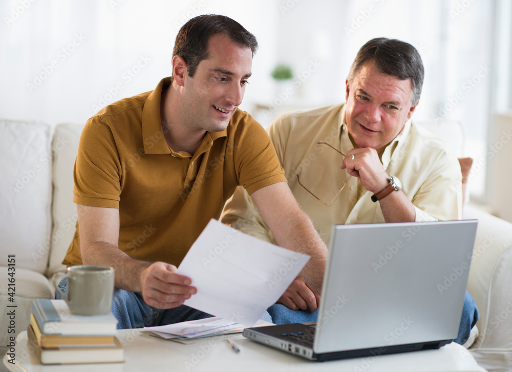 USA, New Jersey, Jersey City, Father and son using laptop in living room USA, New Jersey, Jersey City, Father and son using laptop in living room