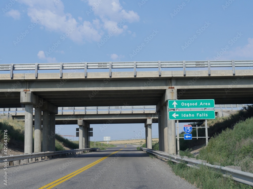Bridges over the road with signs on the road leading to directions to Osgood Area and Idaho Falls, Idaho.