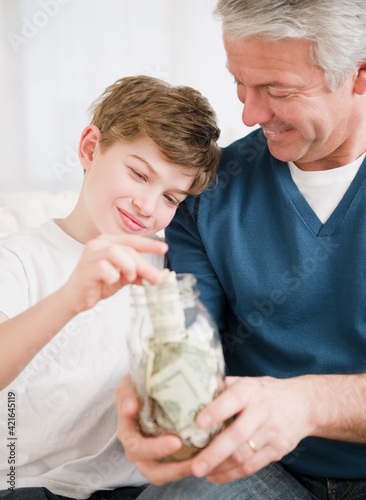 Father and son putting money in jar photo