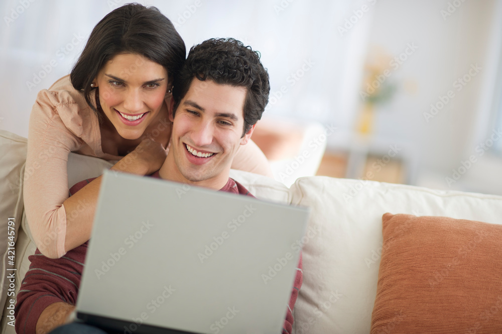 Couple using laptop on sofa Couple using laptop on sofa