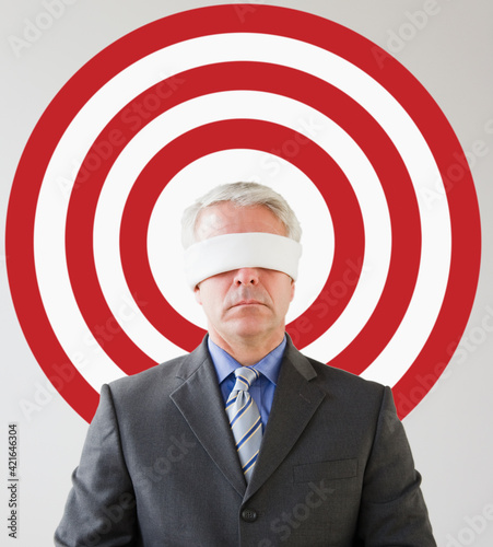 Blindfolded man standing in front of bull's eye