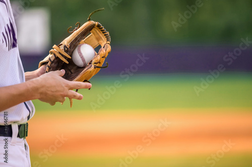 Cuadro en lienzo A young adult male baseball player holding a baseball glove and baseball ball in his glove