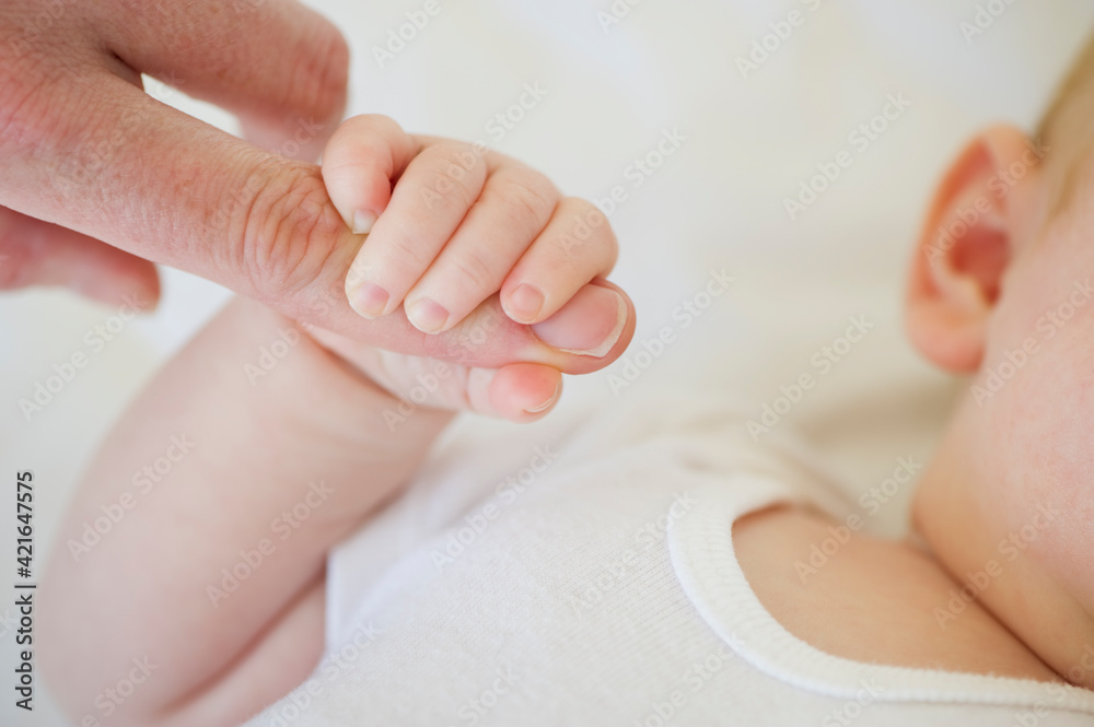 Infant holding onto adult's finger Infant holding onto adult's finger