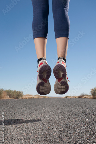 USA, Arizona, Winslow, Mid adult woman jumping, low section