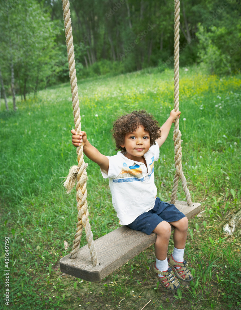 Young child sitting on large outdoor swing Young child sitting on large outdoor swing