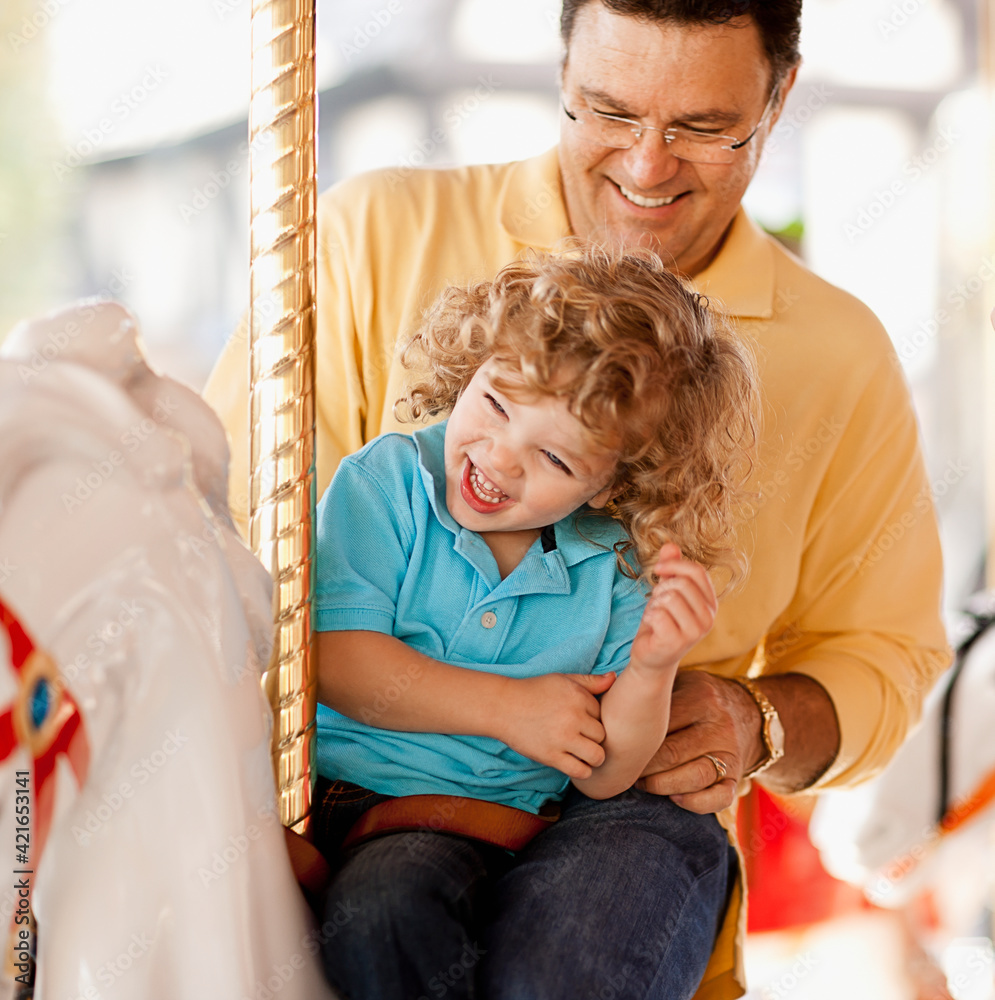 USA, California, Los Angeles, Father with son (4-5) sitting on carousel's horse USA, California, Los Angeles, Father with son (4-5) sitting on carousel's horse