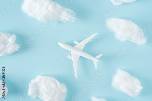 White jet airplane flying between the fluffy clouds. Travel around the world creative concept