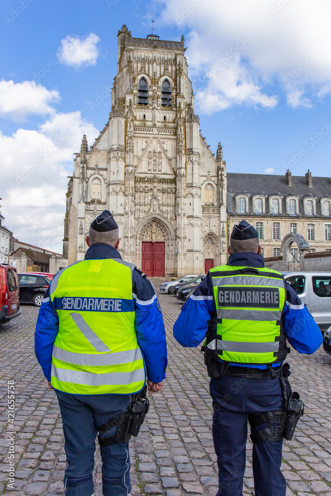 Fototapeta premium Deux Gendarmes, de dos, devant l'Abbaye de Saint-Riquier, Somme, France