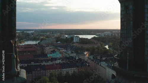 Flying through church towers in Stockholm, Sweden. A summer evening with an aerial view above an urban city with rooftops and the sea of Mälaren and Baltic Sea.