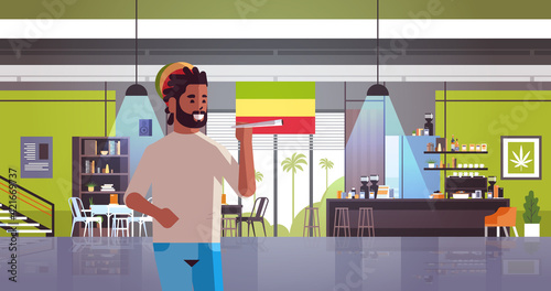 african american guy smoking marijuana joint rastaman relaxing with weed cigarette coffeeshop interior portrait horizontal