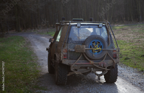 Fotografie Closeup of a four-wheel drive covered in mud, on a path to the forest