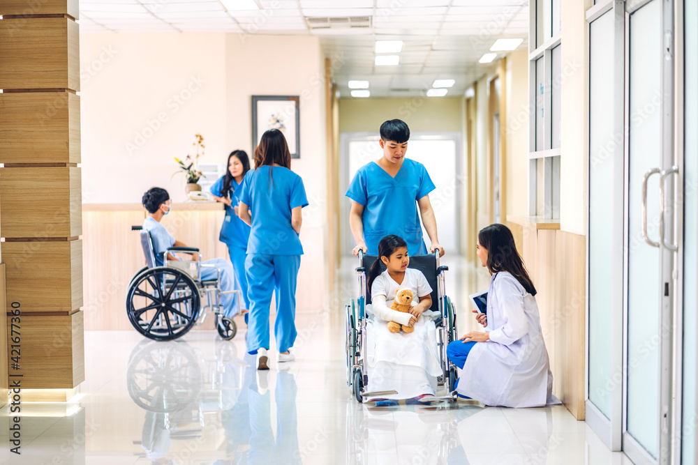Group of professional medical doctor team with stethoscope in uniform service help support discussing and consulting talk to little girl patient in wheelchair and check up information in hospital