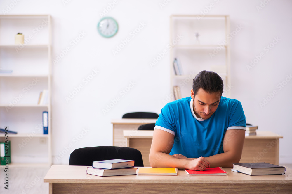 Exhausted male student preparing for the exams in the classroom Exhausted male student preparing for the exams in the classroom