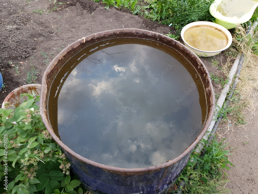 a container with water with a reflection of the sky stands on the ground a container with water with a reflection of the sky stands on the ground