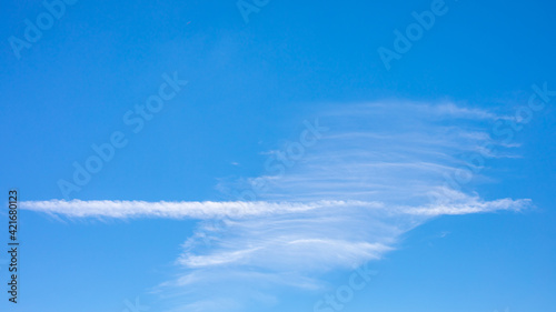 White clouds and white smoke trail of air plane on the clear blue sky. © Phongsak