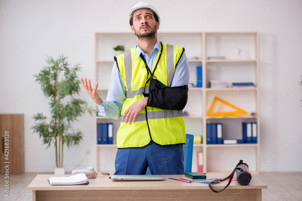Young arm injured male architect working in the office Young arm injured male architect working in the office