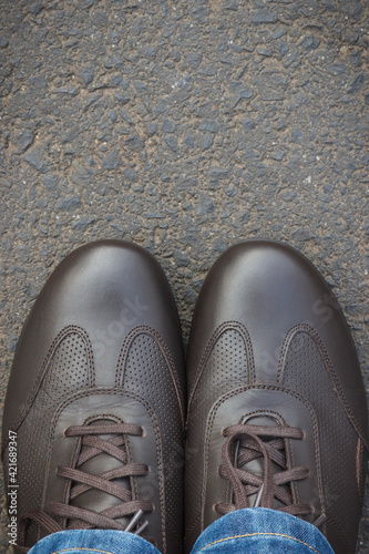 Comfortable brown leather shoes for men on asphalt road or footpath. Male footwear. Copy space for text