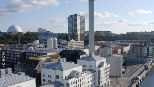 Stockholm, Sweden. Aerial Drone view of a white industry complex with chimney, the canal at Hammarby Sjöstad with modern architecture. high towers and globe structure.