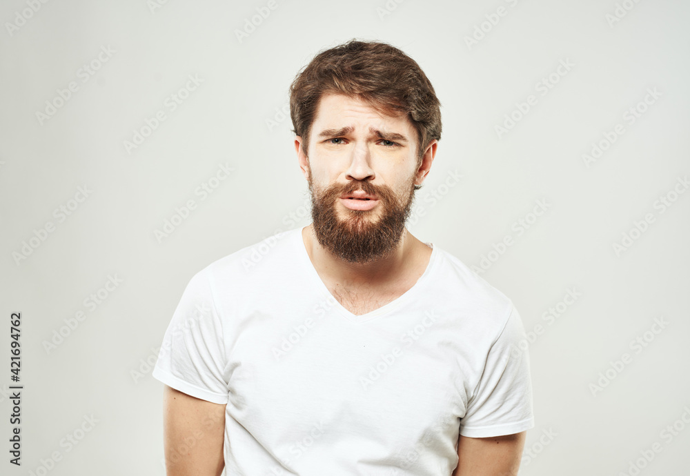 Guy in a white T-shirt on a light background emotions sad face cropped view Guy in a white T-shirt on a light background emotions sad face cropped view