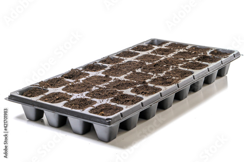 Black cassette for seedlings on a white background illed with humus soil. photo