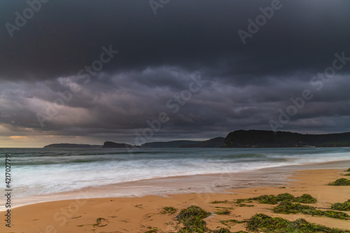 Drizzly sunrise seascape with seaweed on the beach