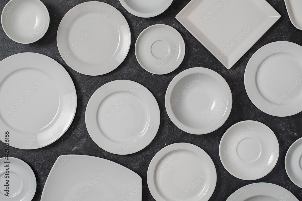 Many white empty plate on black background, close up Many white empty plate on black background, close up