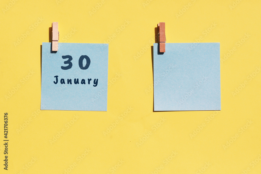 30 January. 30th day of the month, calendar date. Two blue sheets for writing on a yellow background. Top view, copy space. Winter month, day of the year concept 30 January. 30th day of the month, calendar date. Two blue sheets for writing on a yellow background. Top view, copy space. Winter month, day of the year concept