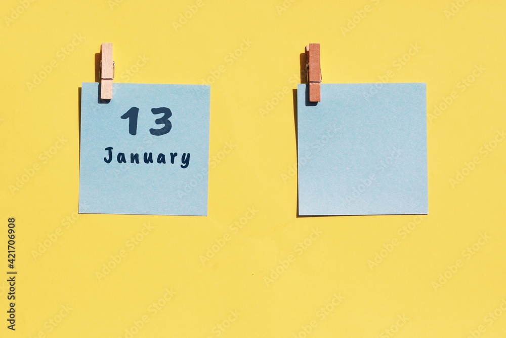 13 January. 13th day of the month, calendar date. Two blue sheets for writing on a yellow background. Top view, copy space. Winter month, day of the year concept 13 January. 13th day of the month, calendar date. Two blue sheets for writing on a yellow background. Top view, copy space. Winter month, day of the year concept