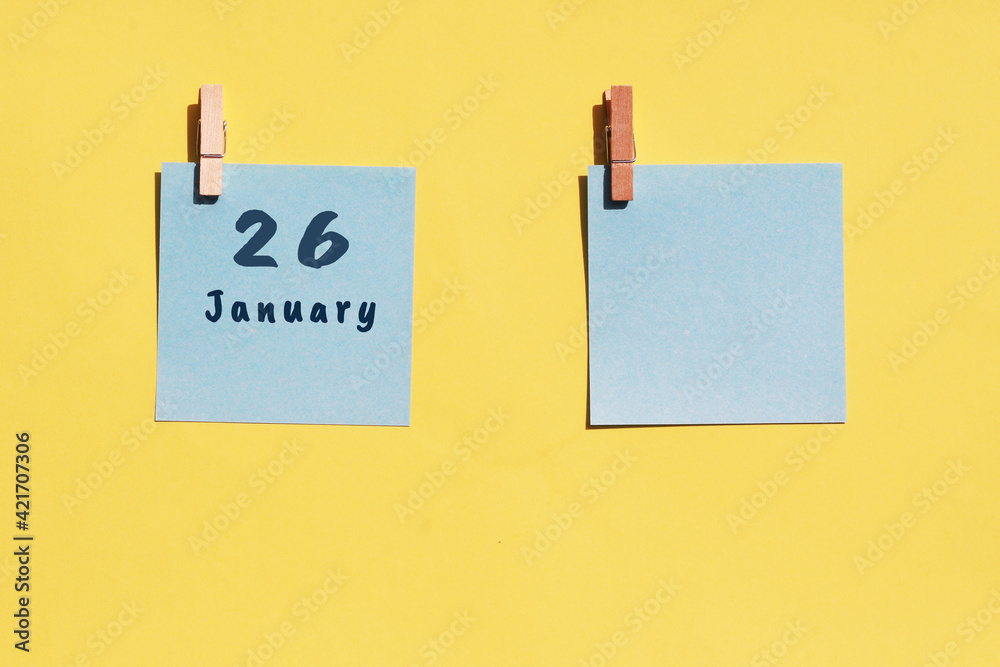 26 January. 26th day of the month, calendar date. Two blue sheets for writing on a yellow background. Top view, copy space. Winter month, day of the year concept 26 January. 26th day of the month, calendar date. Two blue sheets for writing on a yellow background. Top view, copy space. Winter month, day of the year concept