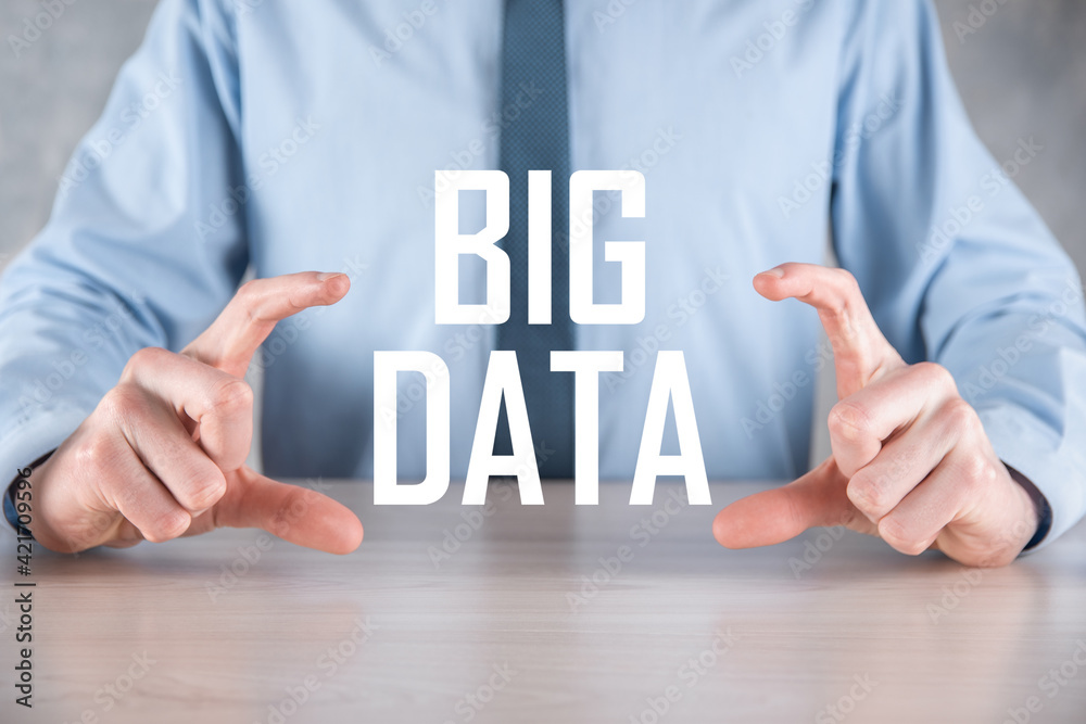 Businessman in a suit on a dark background holds the inscription BIG DATA. Storage Network Online Server Concept.Social network or business analytics representation