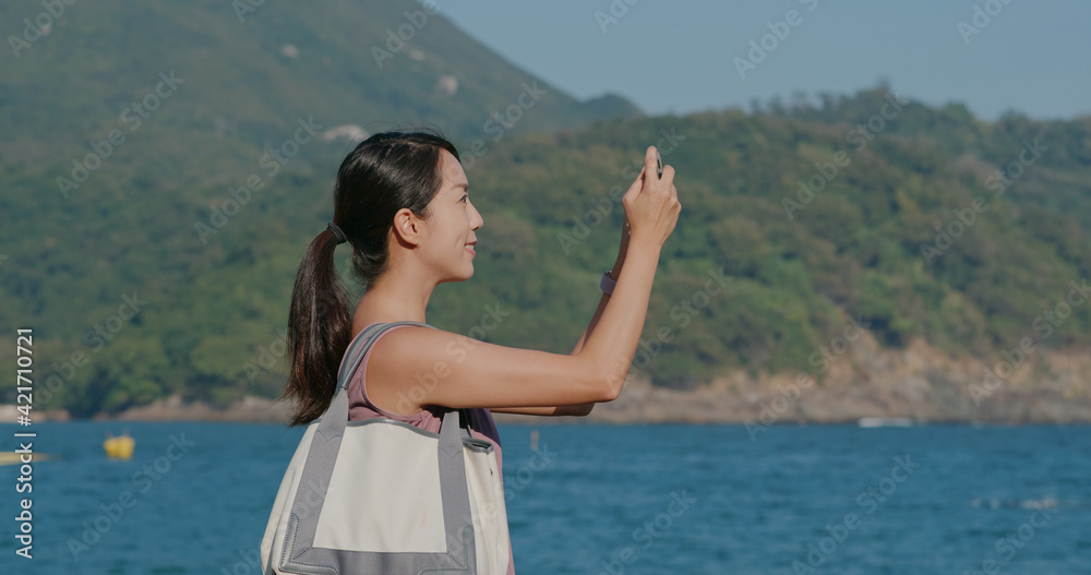 Sport woman use cellphone to take photo with sea view