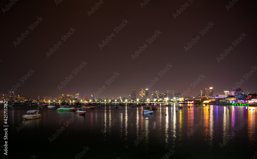 Ships and Ferries in Pattaya City Marina Bay at Night with the City skyline in the background Thailand