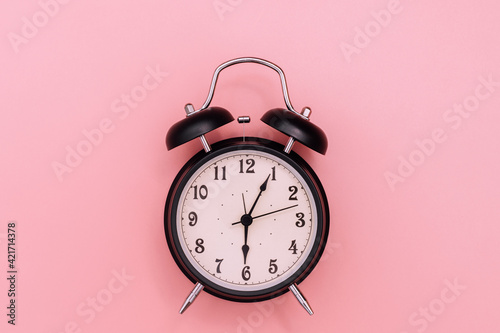 Black alarm clock on pink background