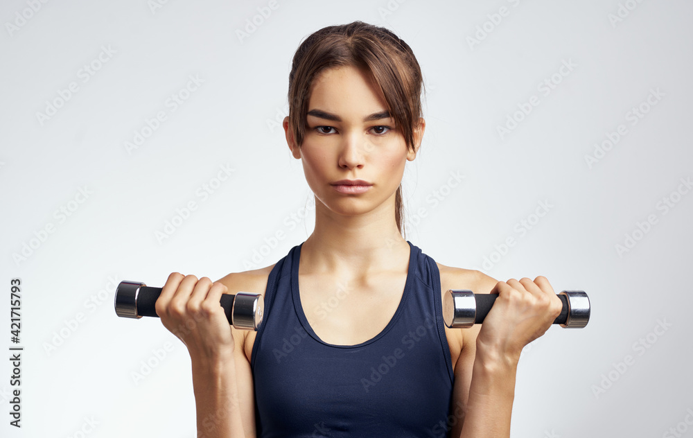 woman with dumbbells in hand on light background cropped view of short t-shirt fitness woman with dumbbells in hand on light background cropped view of short t-shirt fitness