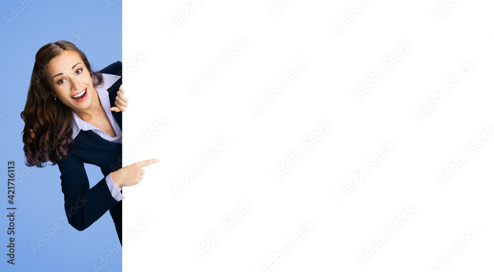 Happy excited woman in black confident suit showing pointing blank white banner signboard. Business and advertising concept. Copy space empty place for text. Blue color background.. Happy excited woman in black confident suit showing pointing blank white banner signboard. Business and advertising concept. Copy space empty place for text. Blue color background..
