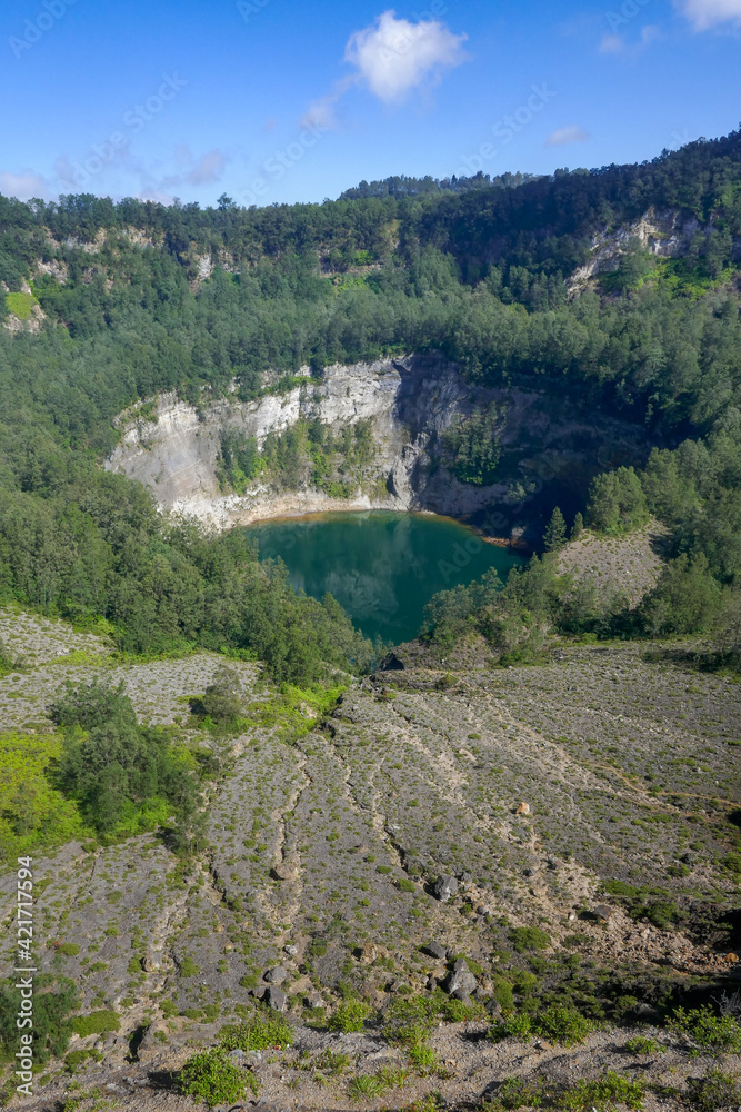 Fototapeta premium View of isolated crater with green lake on top of Kelimutu volcano, famous national park on Flores island, East Nusa Tenggara, Indonesia