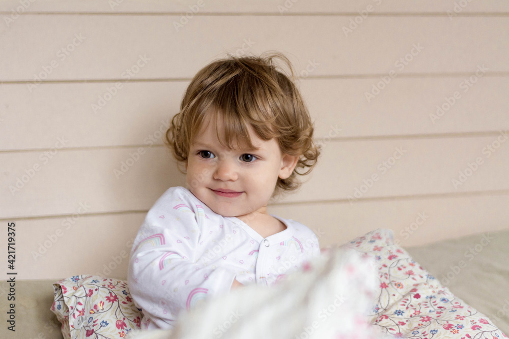 Portrait of a little smiling child in white clothes on the bed Portrait of a little smiling child in white clothes on the bed