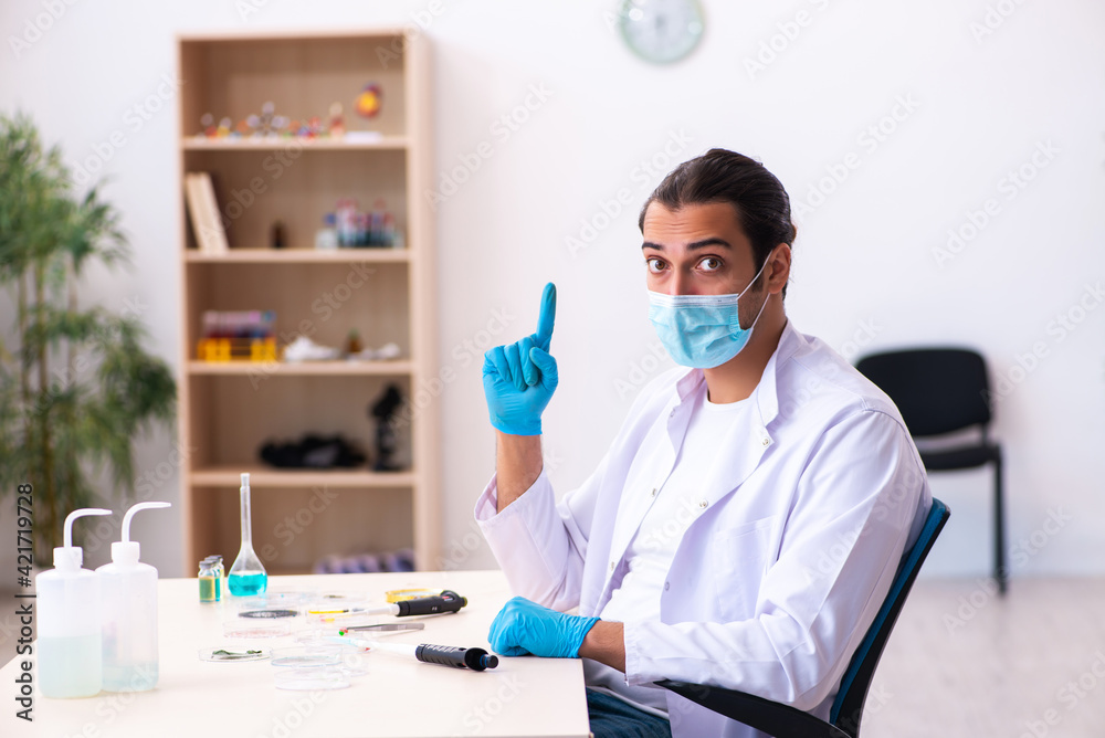 Young male chemist working in the lab during pandemic