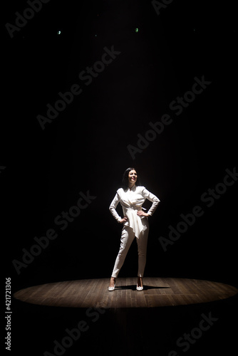 model in a white suit on stage in a beam of white light © nagaets